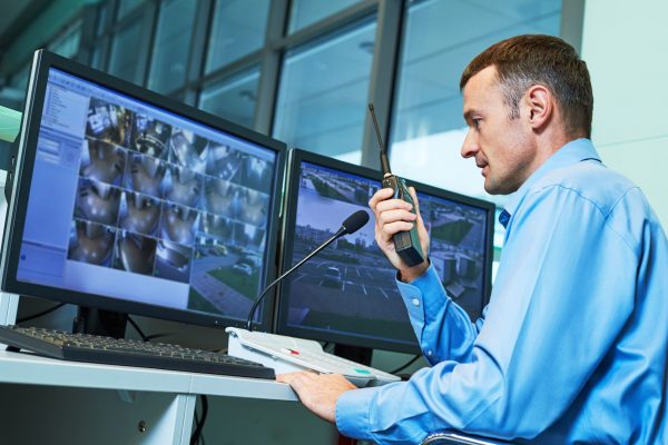 Security-guard-working-monitoring-screens-dual-monitors-systems-surveillance